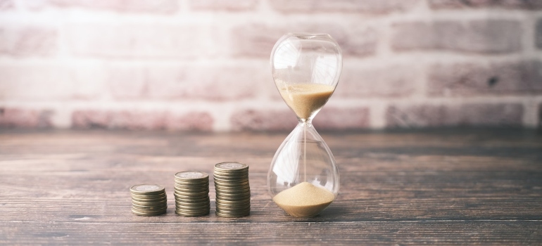 Stacks of coins next to an hourglass.