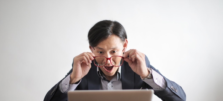 Amazed businessman holding red rimmed glasses.