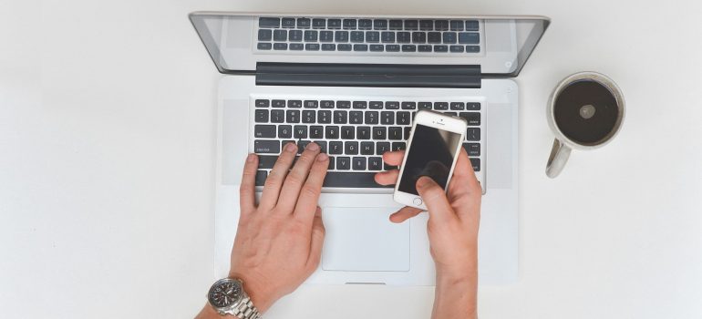 A man holding a phone and working on a laptop.