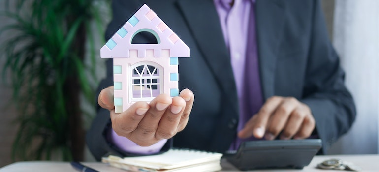 A person holding a model of the house