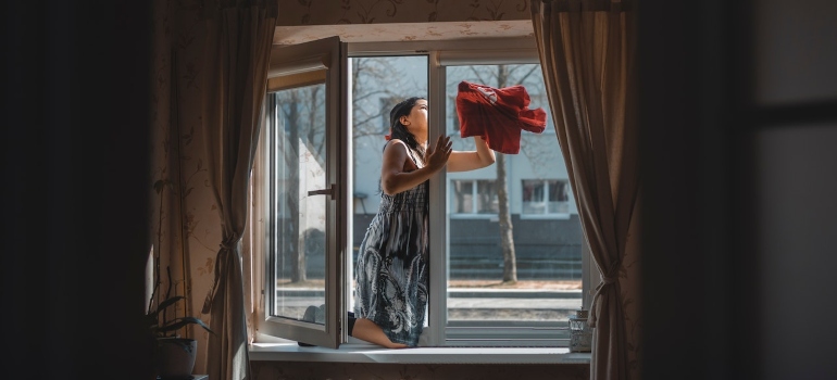 a woman cleaning the windows after inheriting a house full of stuff